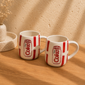 Set of 2 handmade Diet Coke mugs in hand-painted red and cream ceramic on a wooden table